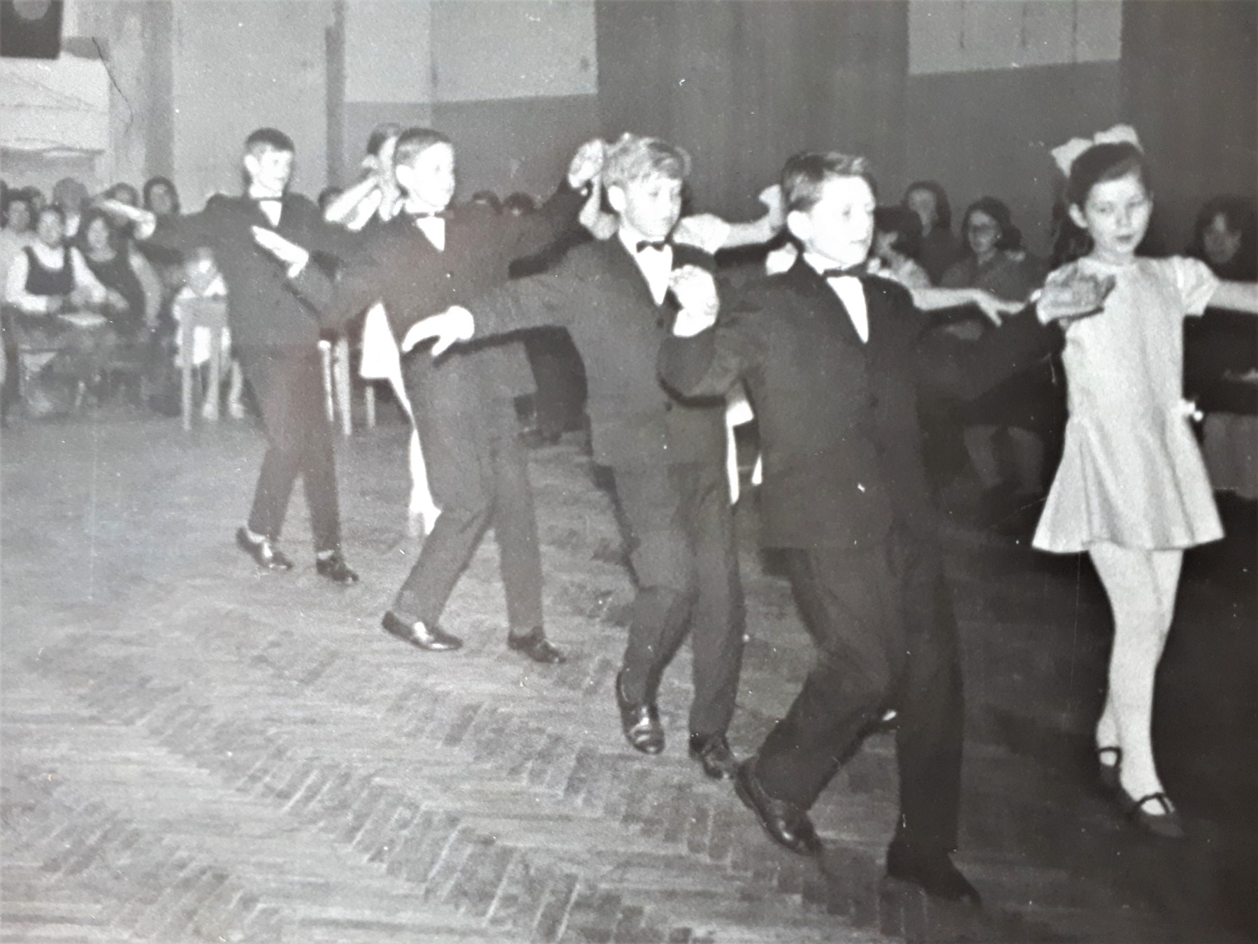 Archival photograph of children dancing, with Aigars in the foreground on the right